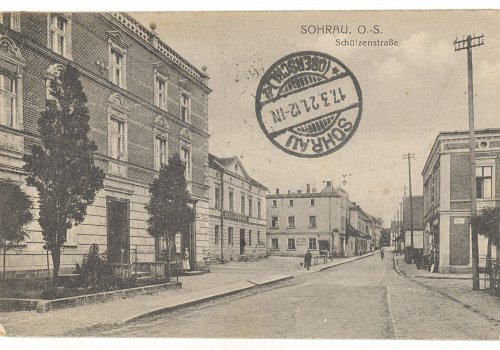 Numer inwentarzowy: MŻo/549; Materiał: papier; Technika: drukarska; Wymiary: wysokość &ndash; 9,1 cm, szerokość &ndash; 13,7 cm; Datowanie: 1921 r.; Wydawca: Franz Polloczek, Sohrau (Żory) 
Poczt&oacute;wka czarno-biała, w układzie poziomym, obiegowa, przedstawiająca zabudowania przy ulicy Strzeleckiej (obecnie Kościuszki) w Żorach. 
Na rewersie dwa znaczki pocztowe wydane przez Międzysojuszniczą Komisję Rządzącą i Plebiscytową na G&oacute;rnym Śląsku. 
Poczt&oacute;wka o zabarwieniu propagandowym, nadana 17 marca 1921 roku z Żor (Sohrau), czyli na trzy dni przed planowanym Plebiscytem na G&oacute;rnym Śląsku, kt&oacute;rego wyniki zadecydować miały o jego przynależności państwowej. Na rewersie wydrukowany fragment wiersza autorstwa niemieckiego pisarza Ernsta Morisa Arndta z 1812 r. dla upamiętnienia Plebiscytu z Żorach.&nbsp;&nbsp; &nbsp;