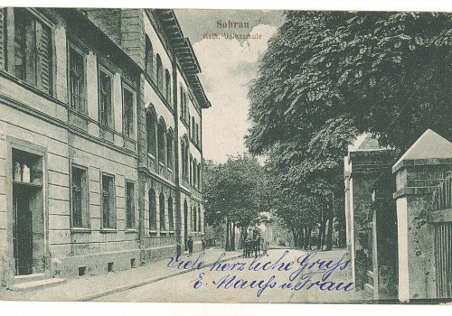Numer inwentarzowy: MŻo/1332; Materiał: papier; Technika: drukarska; Wymiary: wysokość &ndash; 8,7 cm, szerokość &ndash; 13,7 cm; Datowanie: 1920-21; Wydawca: Franz Polloczek, Sohrau (Żory) 
Poczt&oacute;wka czarno-biała, w układzie poziomym, obiegowa, przedstawiająca fragment budynku szkoły katolickiej w Żorach. Poczt&oacute;wka nadana z Żor do Kopenhagi 7 października 1921 roku, na rewersie naklejone cztery znaczki pocztowe wydane przez Międzysojuszniczą Komisję Rządzącą i Plebiscytową na G&oacute;rnym Śląsku.