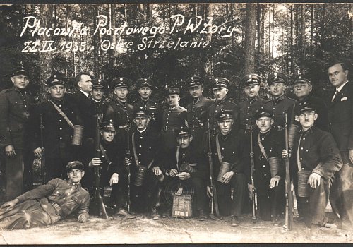 Wymiary: wysokość - 9 cm, szerokość - 14 cm; Materiał: papier fotograficzny; Technika: fotograficzna; Pochodzenie: Żory, G&oacute;rny Śląsk; Datowanie: 1935 r.; Autor: brak danych 
Fotografia czarno-biała przedstawiająca portret zbiorowy żorskich listonoszy i żołnierzy w trakcie ćwiczeń strzeleckich w ramach przysposobienia wojskowego. Na fotografii uwieczniono siedmiu listonoszy w umundurowaniu i z karabinami, dziewięciu żołnierzy (oficer&oacute;w) oraz dw&oacute;ch mężczyzn w ubraniach cywilnych. W prawym g&oacute;rnym rogu napis:&nbsp;Plac&oacute;wka Pocztowego P.W. Żory 22 IX 1935. Ostre Strzelanie. Na rewersie odręczny napis długopisem:&nbsp;Marciniec.